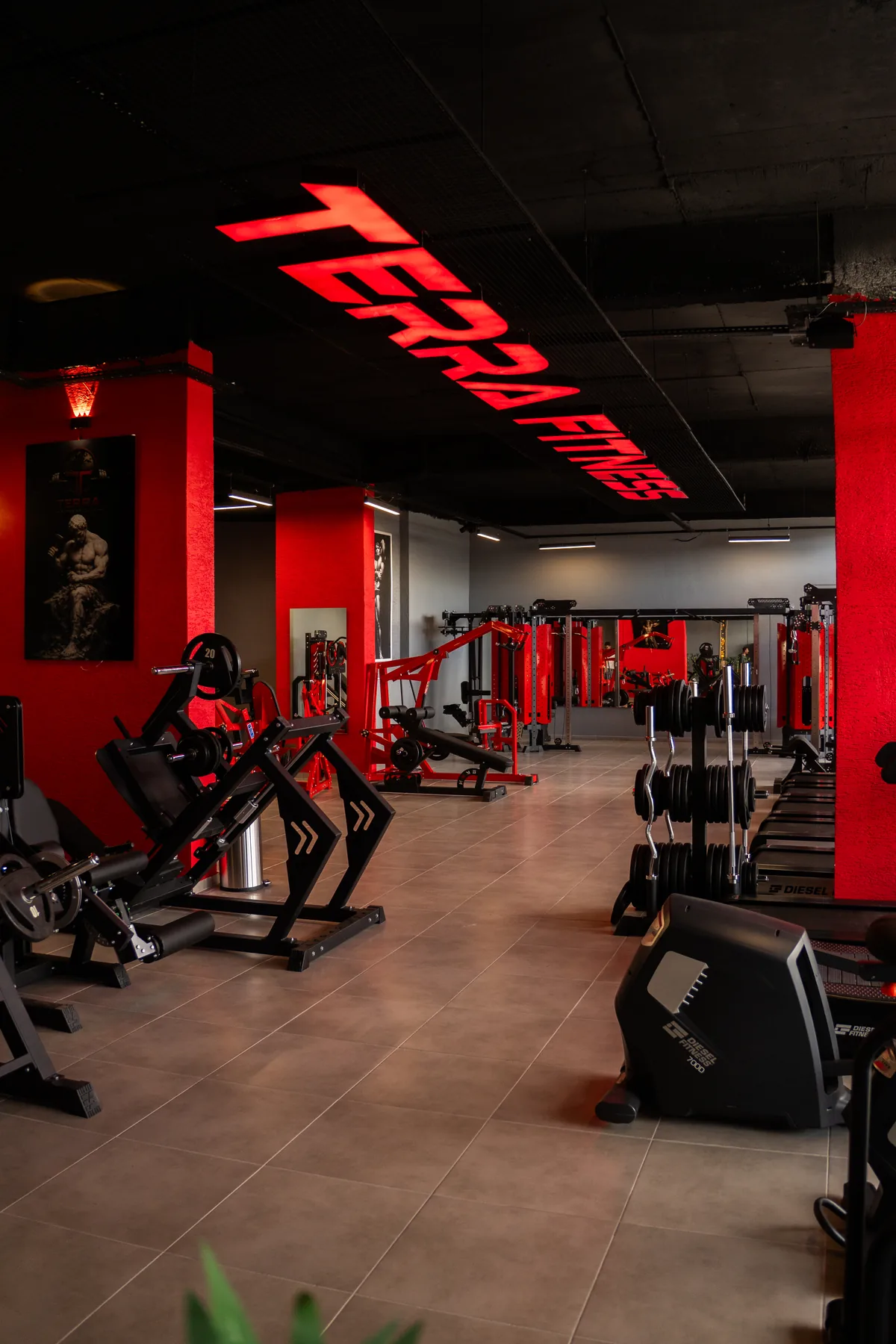 Terra Fitness Club’ın kırmızı kolonları arasında ağırlık ve fitness ekipmanları